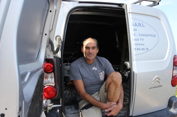 Philippe Requena sitter i den öppna bakdörren på en firmabil.