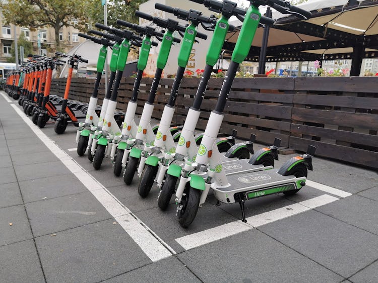 En lång rad parkerade elsparkcyklar i stadsmiljö.