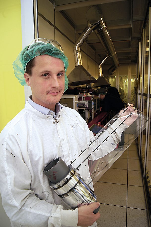 En person i labbkläder håller i en rulle med genomskinligt material.