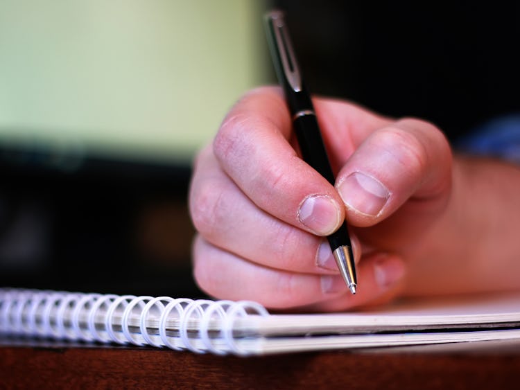 En hand som håller i en penna över ett skrivblock