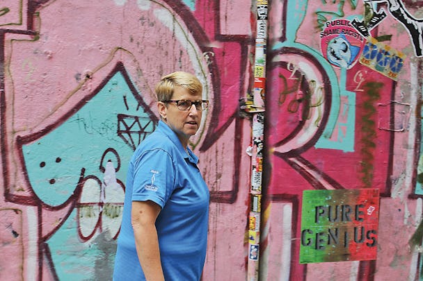 Erin i halvfigur, stående framför en vägg med graffiti.