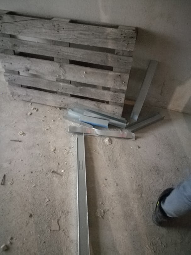 Ett skräpigt golv med en lastpall lutad mot en vägg.
