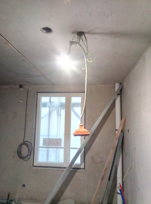 EN lampa som hänger från ett tak i ett kalt rum.