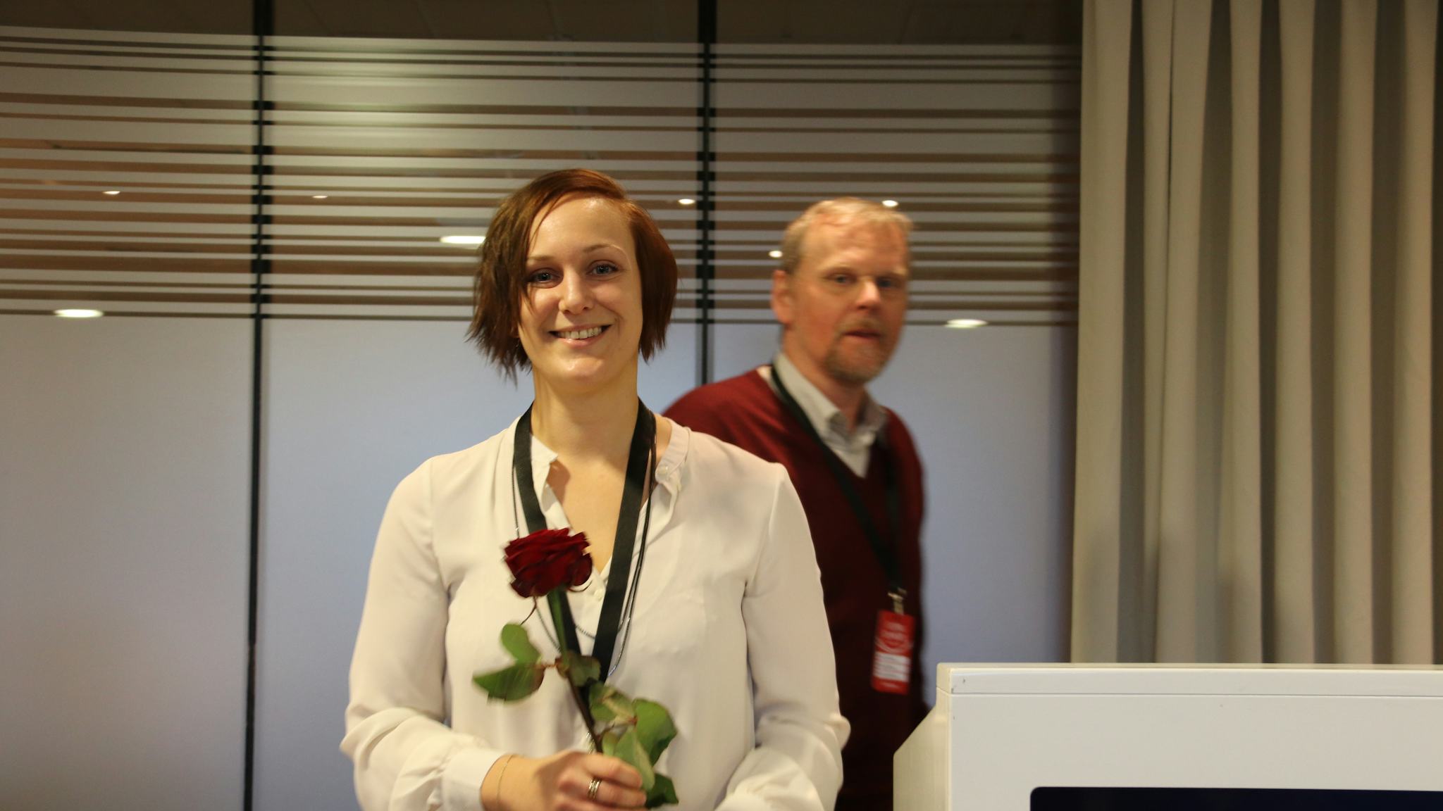 Louise Olsson leende med en ros i händerna.