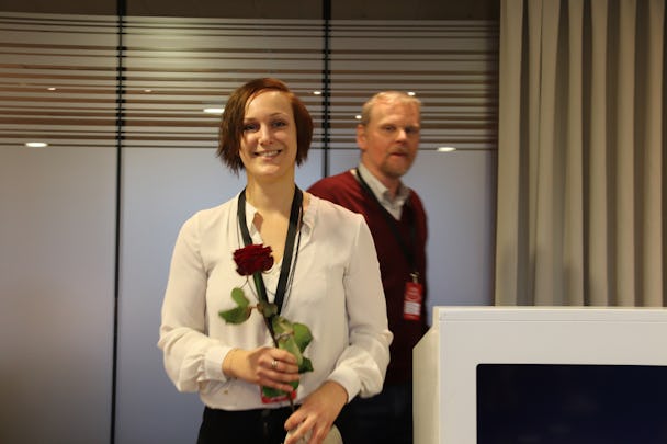 Louise Olsson leende med en ros i händerna.