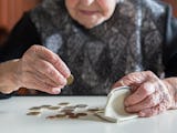 En äldre person räknar mynt på ett bord