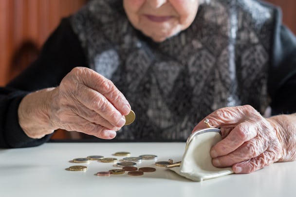 En äldre person räknar mynt på ett bord