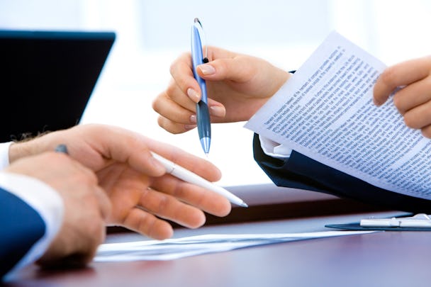 Två par händer som håller i pennor och papper i ett möte