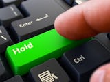 Ett finger ovanför en grön tangentbordsknapp med ordet "Hold" på