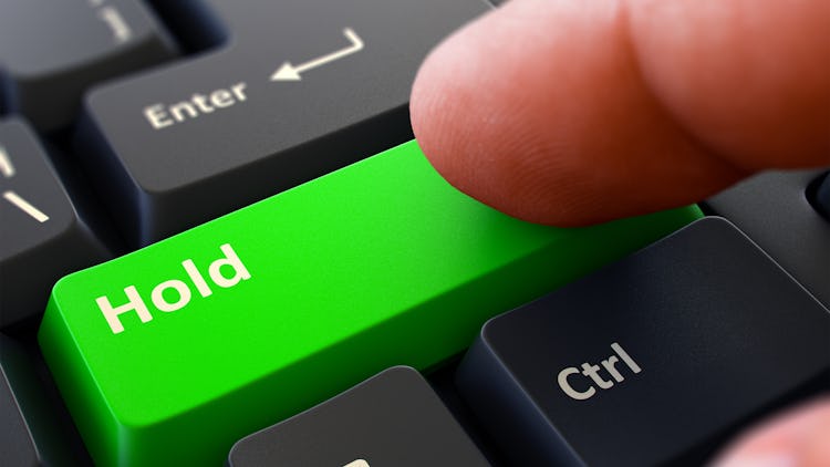 Ett finger ovanför en grön tangentbordsknapp med ordet "Hold" på