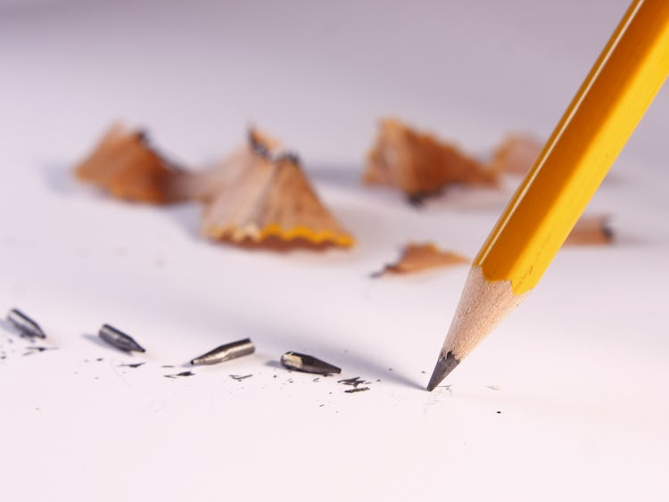 En blyertspenna mot ett papper, omgiven av penn-spån.