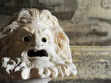 En grekisk antik skulptur av ett ilsket ansikte med svallande hår