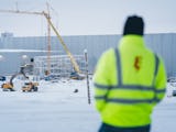 Mathias Hansson utomhus i snön, med arbetsplatsen i bakgrunden