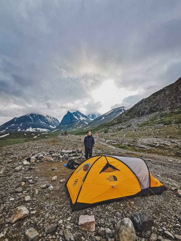 En person invid ett tält på en bergsplätt