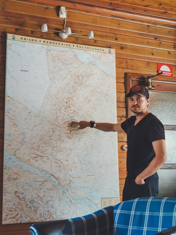 Anton Levein pekar på en stor karta i en stuga