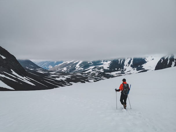 En person vandrar över en snöig slätt mot ett berg