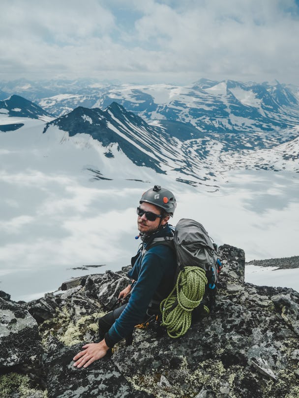 Anton Levein i klätterutrustning på en klippkam framför ett molnigt bergslandskap