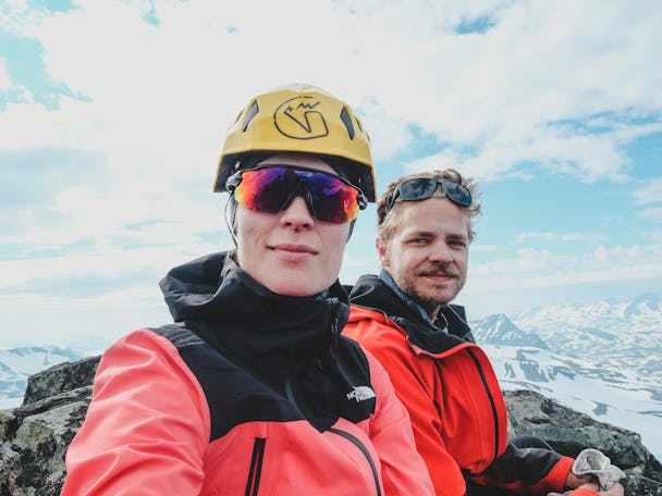 Emma och Anton i klättermundering framför ett dimmigt bergslandskap