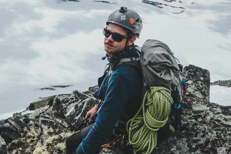 Anton Levein i klätterutrustning på en klippkam framför ett molnigt bergslandskap