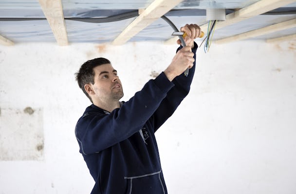 Jonas Isacsson arbetar med sladdar i ett tak