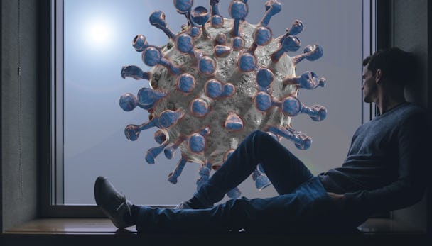 En man sitter i ett fönster och tittar ut på en stiliserad 3D-version av covid-viruset.