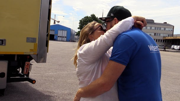 Två personer kysser varandra framför en lastbil
