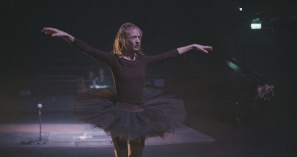 En person i ballett-kläder dansar på en scen