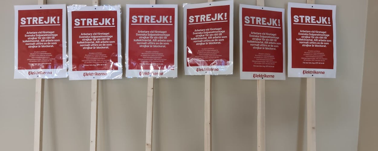 En samling strejkskyltar står lutade mot en vägg