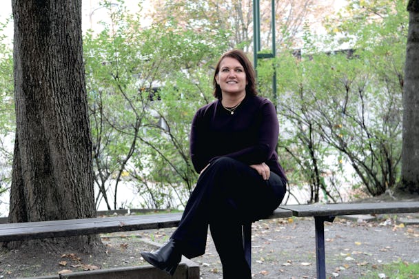 Pernilla Bäckius sitter med benen i kors på en bänk utomhus