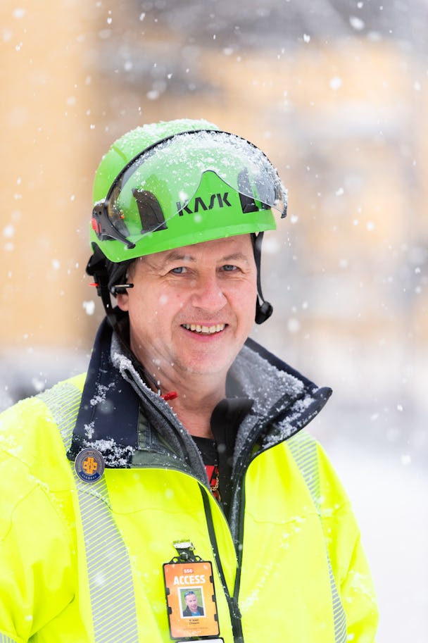Mikael Olsson utomhus i snön, iklädd grön hjälm och gul reflexjacka.