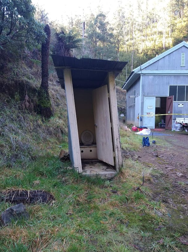 En toalett i ett träskjul utomhus, utan dörr.