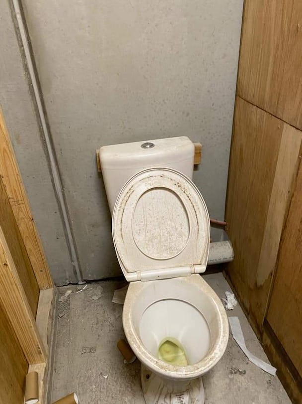 En lortig toalett i ett litet bås.