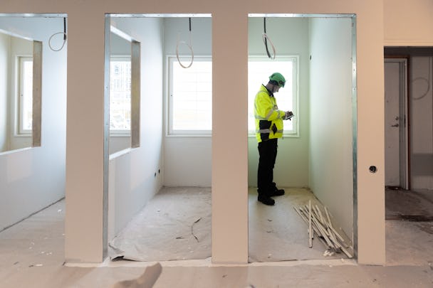 EN person i arbetskläder sedd genom en glasdörr inomhus