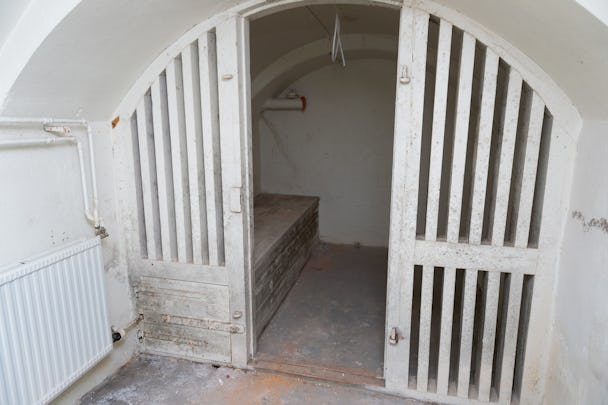 En äldre cell med välvt tak och vita galler.