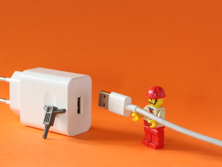 En legofigur kopplar in en USB-sladd i ett uttag.