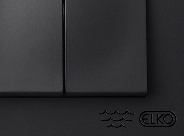 Hörnet på en svart ELKO-apparat där den vågformade märkningen syns.