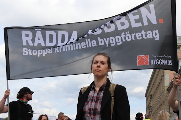 Karolina Dahl framför en banderoll där det står: "Rädda jobben. Stoppa kriminella byggföretag."
