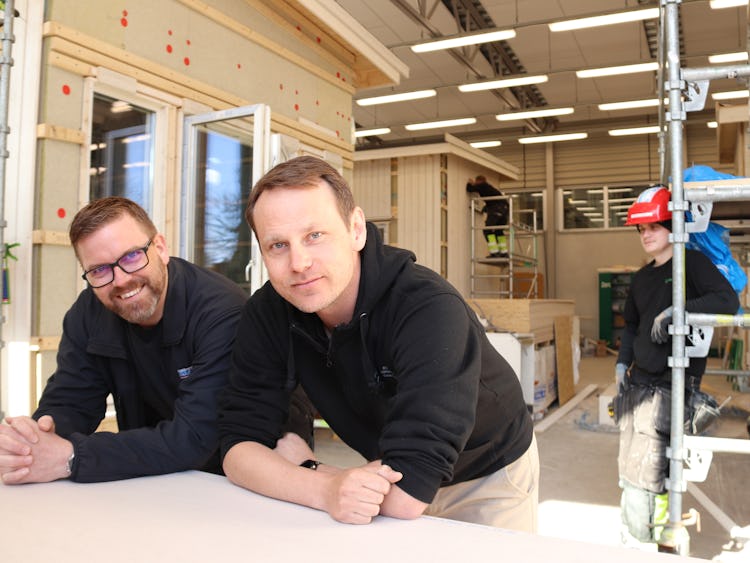 Björn Johnsson och Robert Staaf lutar sig mot ett bord inomhus.