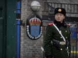 En militär står på vakt, svenska ambassadens logga syns suddigt i bakgrunden.