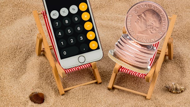 En miniräknare och en hög mynt chillar i varsin solstol på stranden.