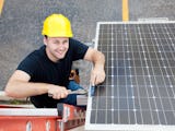 Bild på en glad elektriker som installerar solceller.
