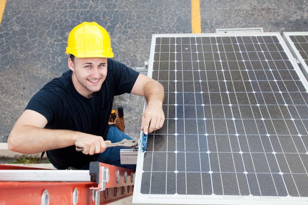Bild på en glad elektriker som installerar solceller.