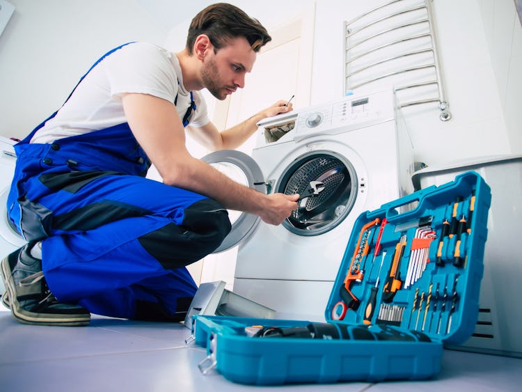 Reparatör som fixar en tvättmaskin.