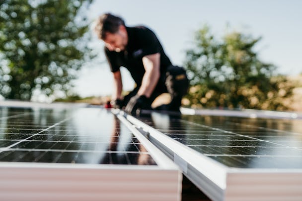 Kille som installerar solpaneler på ett tak, 
