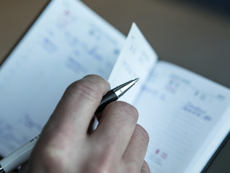 En person som skriver i en anteckningsbok med en penna.