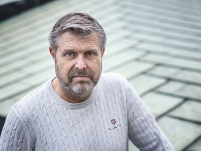 Niklas Enström som står på ett tak i grå tröja.