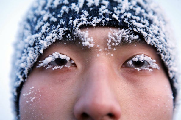 En person som bär en mössa täckt av snö och ögonfransar som gar frusit.
