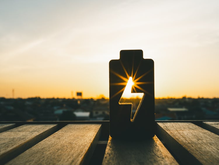En silhuett av ett batteri på ett träbord vid solnedgången.