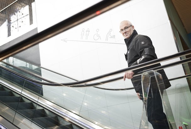 Hans Göthberg som står på en rulltrappa i ett köpcentrum.