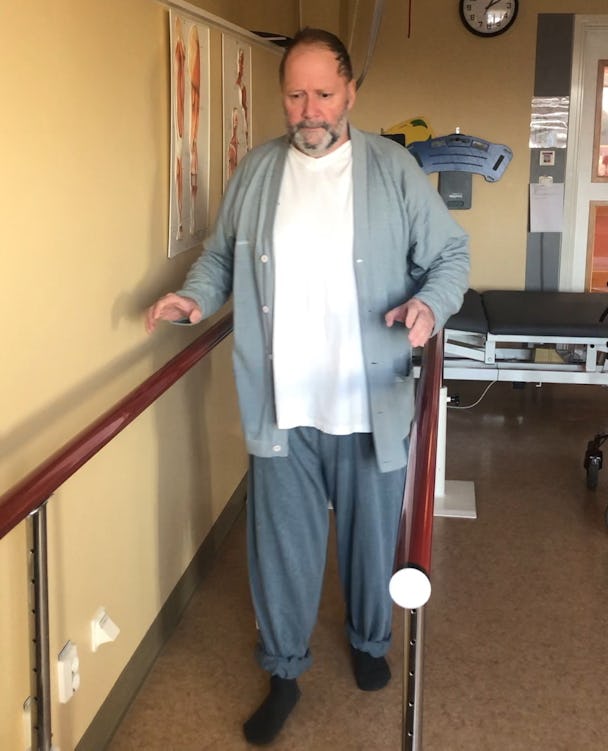 En man som står bredvid ett räcke i ett sjukhusrum.